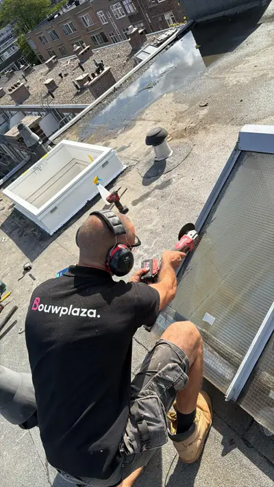 Monteur van Dakraam Montageservice zaagt een sparing voor een nieuw dakraam